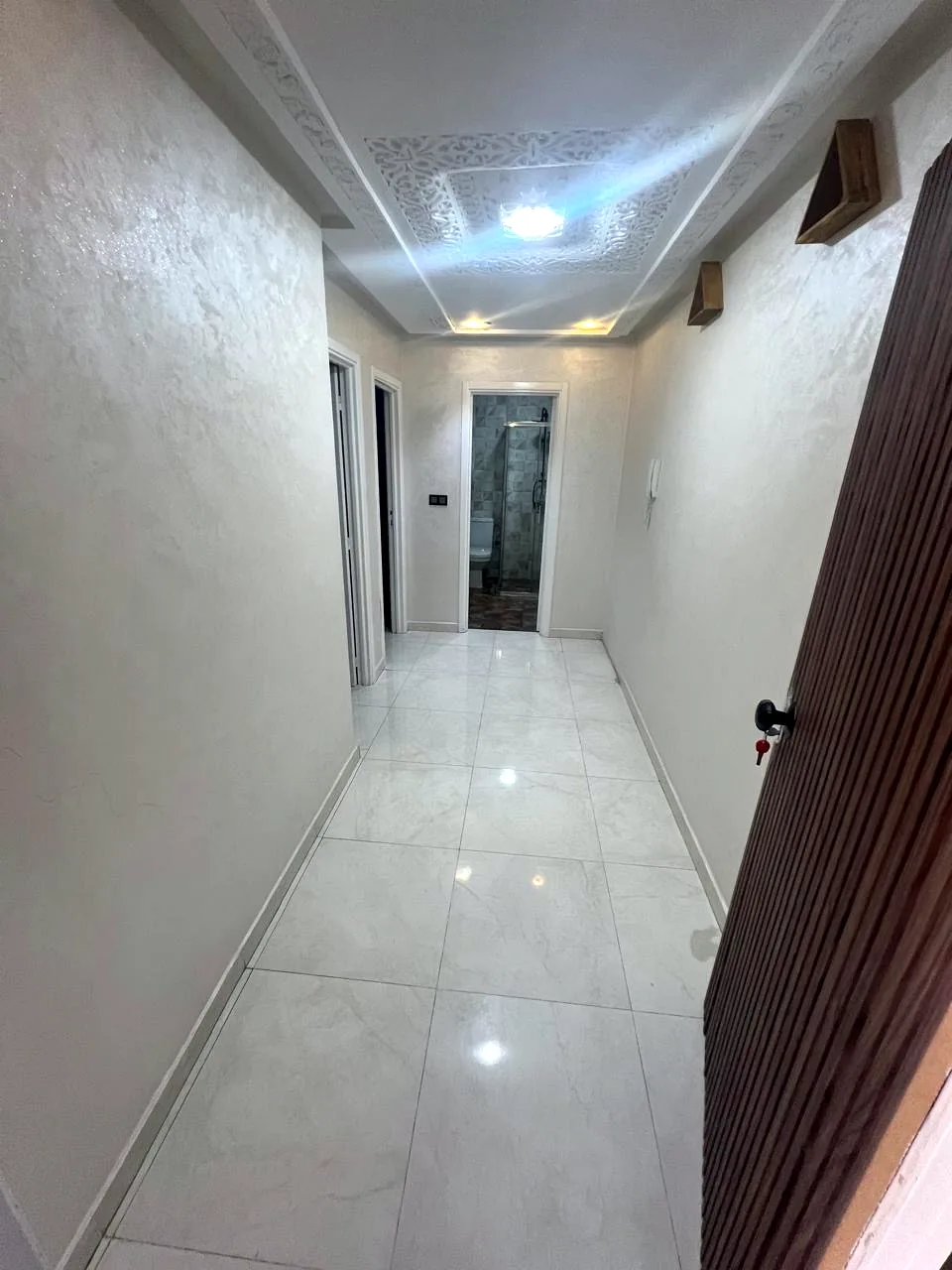 Couloir du studio avec plafond sculpté et appliques murales - Appart'Hôtel Nador De Luxe