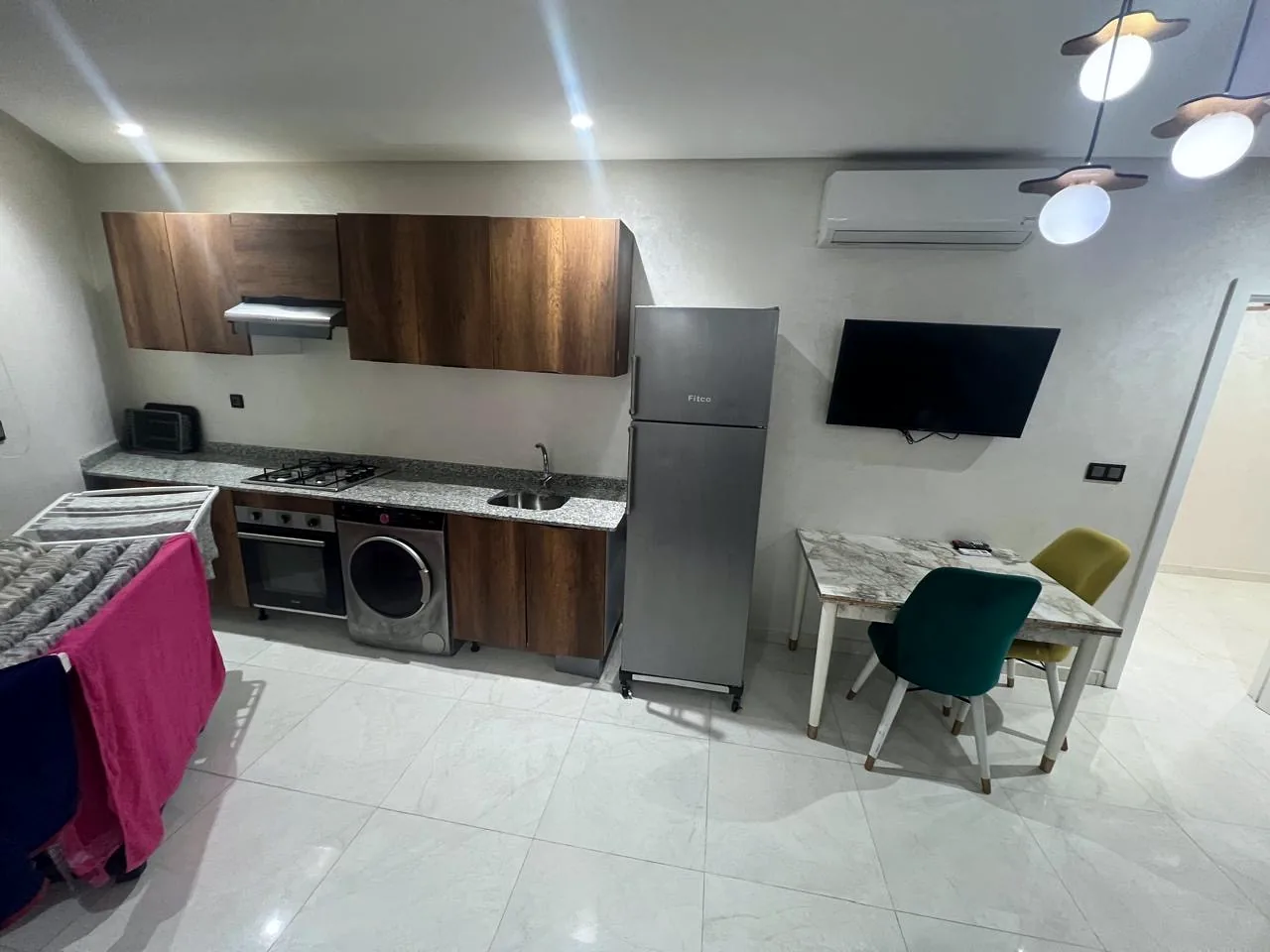 Cuisine équipée ouverte avec coin repas, téléviseur et climatiseur - Appart'Hôtel Nador De Luxe