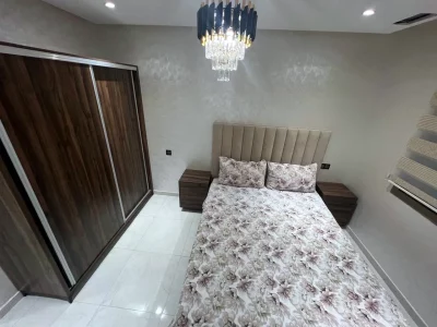 Chambre avec lit double, grande armoire et lustre - Appart'Hôtel Nador De Luxe