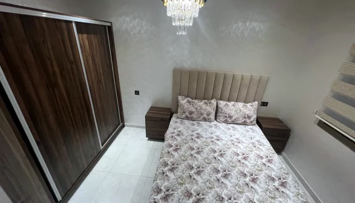 Chambre avec lit double, grande armoire et lustre - Appart'Hôtel Nador De Luxe