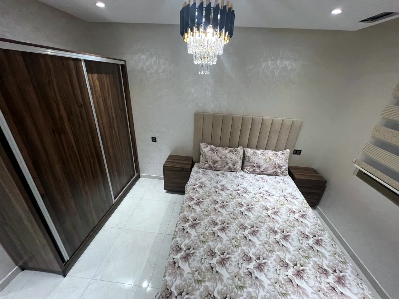 Chambre avec lit double, grande armoire et lustre - Appart'Hôtel Nador De Luxe