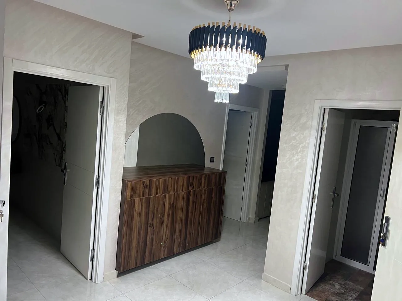 Hall d'entrée avec commode, miroir et lustre en cristal - Appart'Hôtel Nador De Luxe