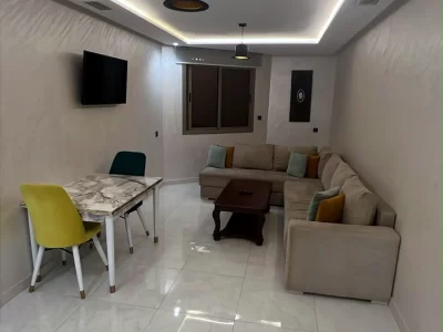 Salon avec canapé d'angle, table à manger et téléviseur - Appart'Hôtel Nador De Luxe