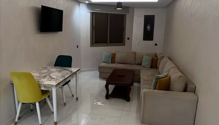 Salon avec canapé d'angle, table à manger et téléviseur - Appart'Hôtel Nador De Luxe