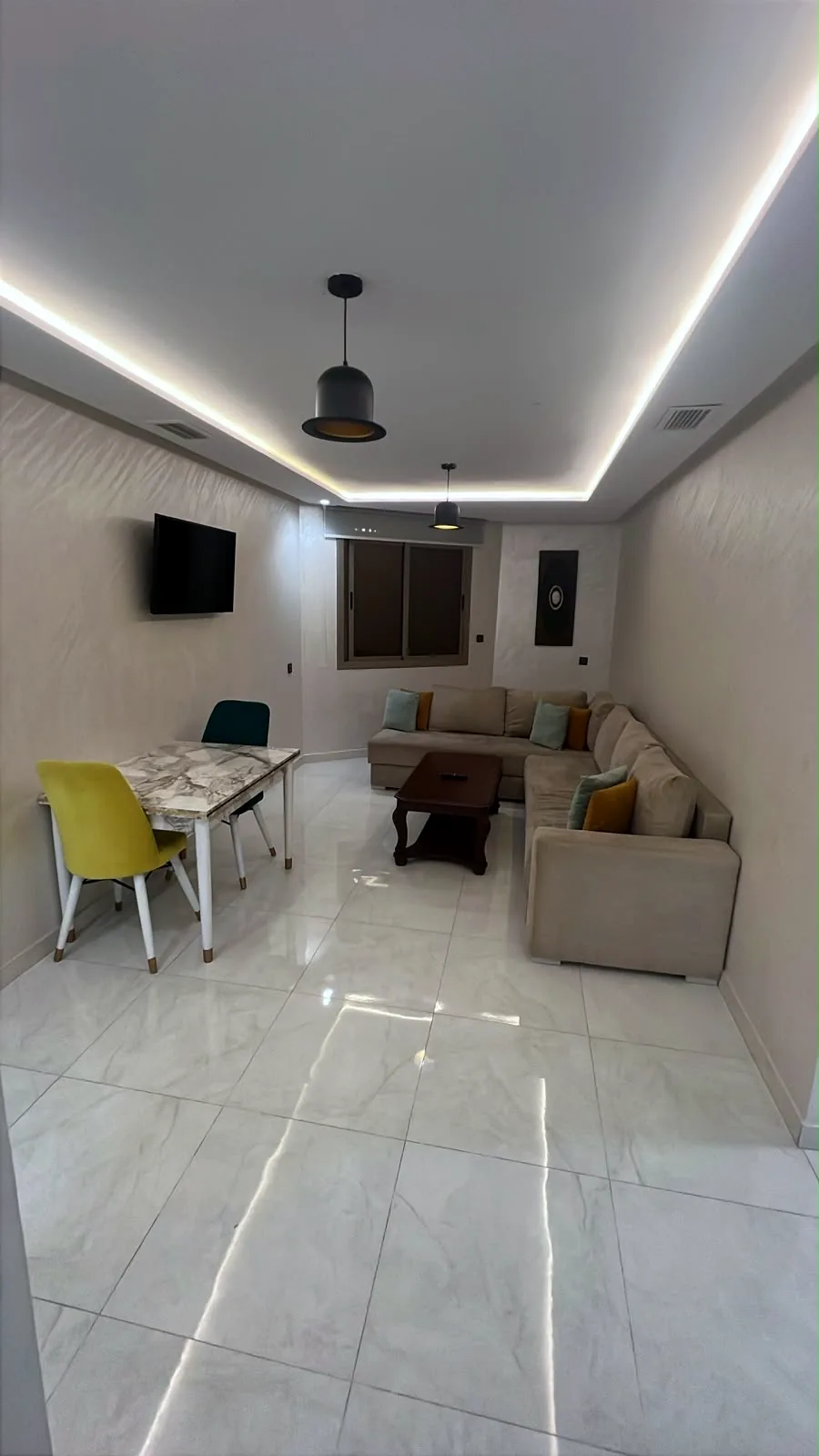 Salon avec canapé d'angle, table à manger et téléviseur - Appart'Hôtel Nador De Luxe