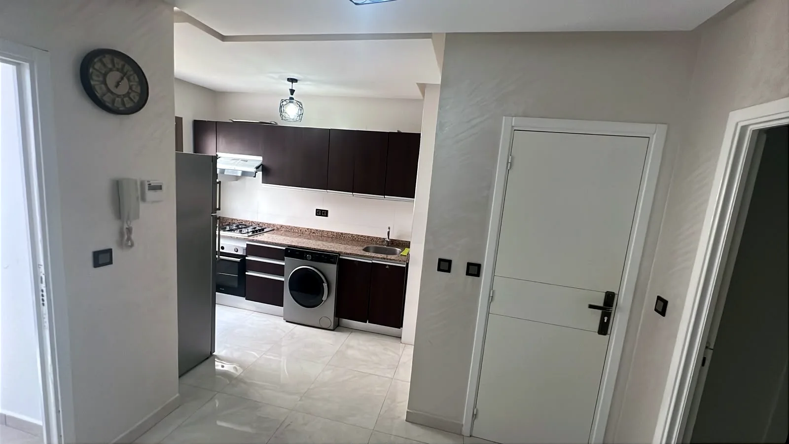 Cuisine équipée vue de l'entrée : four, plaque à gaz, lave-linge et réfrigérateur - Appart'Hôtel Nador De Luxe