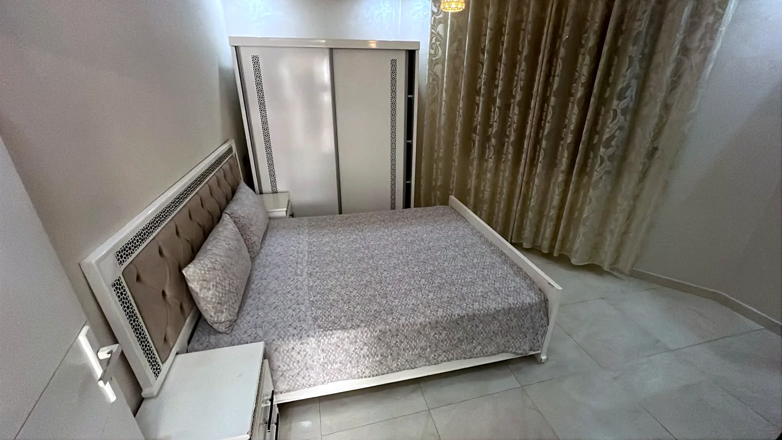 Chambre avec lit double, armoire et rideaux - Appart'Hôtel Nador De Luxe