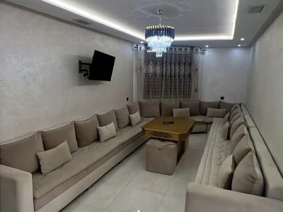 Grand salon marocain avec téléviseur, lustre en cristal et éclairage LED - Appart'Hôtel Nador De Luxe