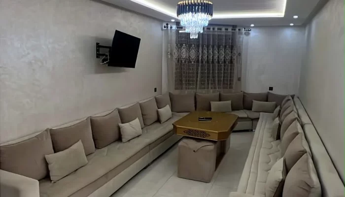 Grand salon marocain avec téléviseur, lustre en cristal et éclairage LED - Appart'Hôtel Nador De Luxe